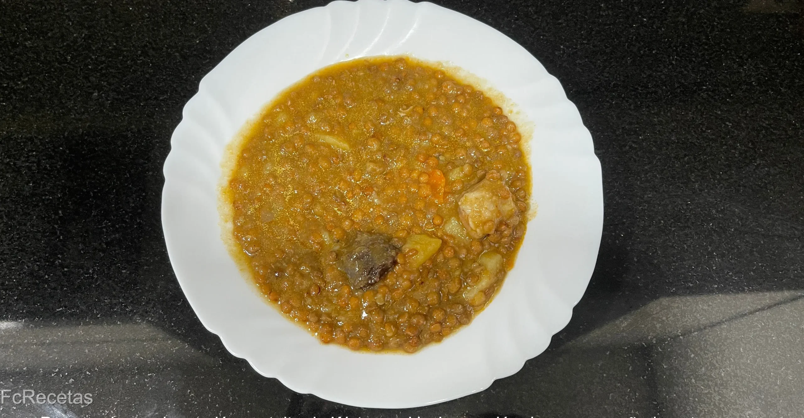 un plato con lentejas estofadas, zanahoria y butifarra