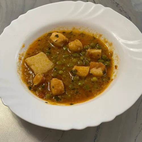 un plato con potón guisado con patatas y guisantes