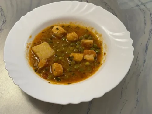 un plato con potón guisado con patatas y guisantes
