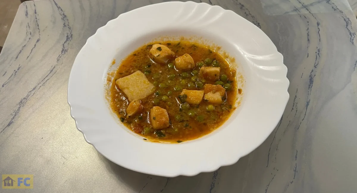 un plato con potón guisado con patatas y guisantes