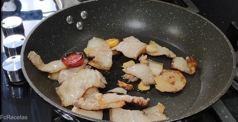 en una sartén salteando panceta y chorizo troceado