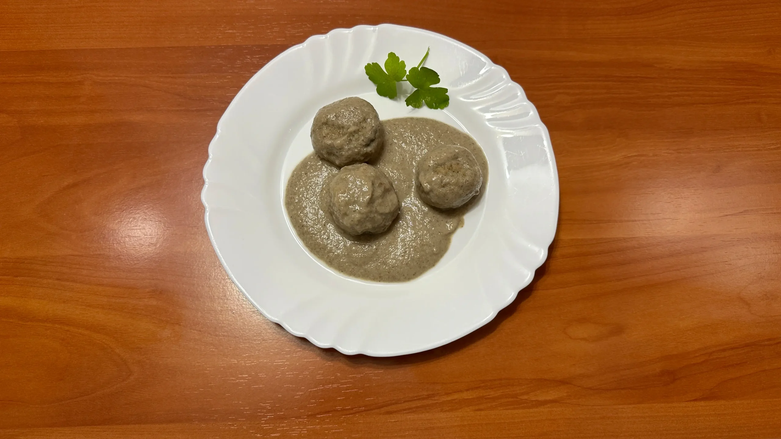en un plato blanco tres albóndiga en salsa de champiñones