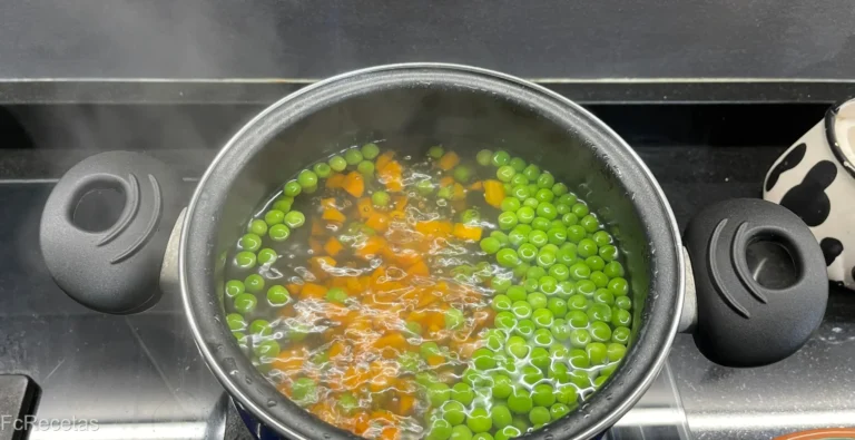 en una cazuela hirviendo guisantes y zanhoria para preparar el arroz tres delicias