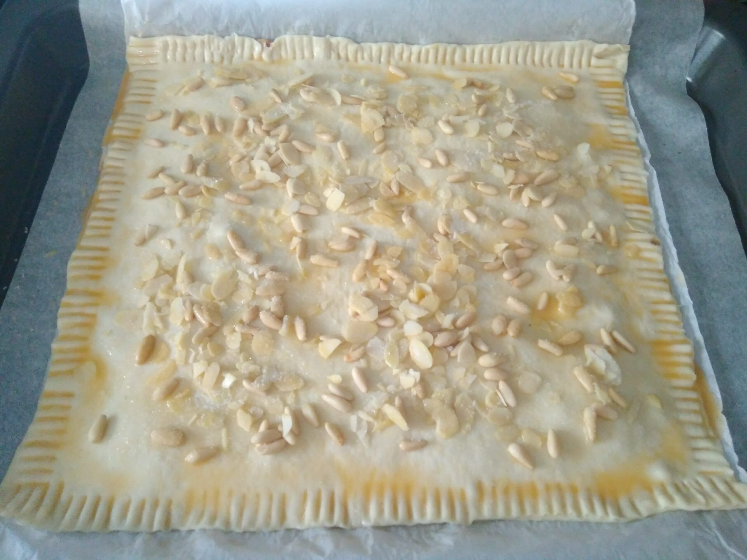 coca de hojaldre con piñones y almendra