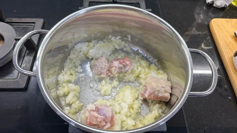 sofregit de costella ceba i all primer pas de la recepta de mongetes vermelles amb xoriço